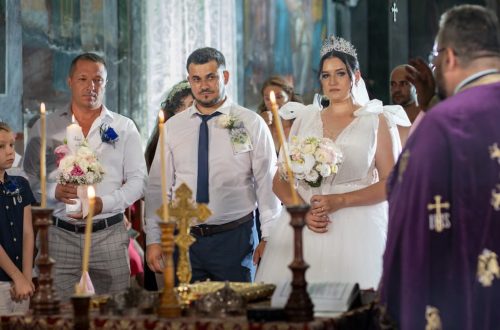 Bride and groom in an ornate church during a traditional wedding ceremony with candles.