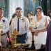 Bride and groom in an ornate church during a traditional wedding ceremony with candles.